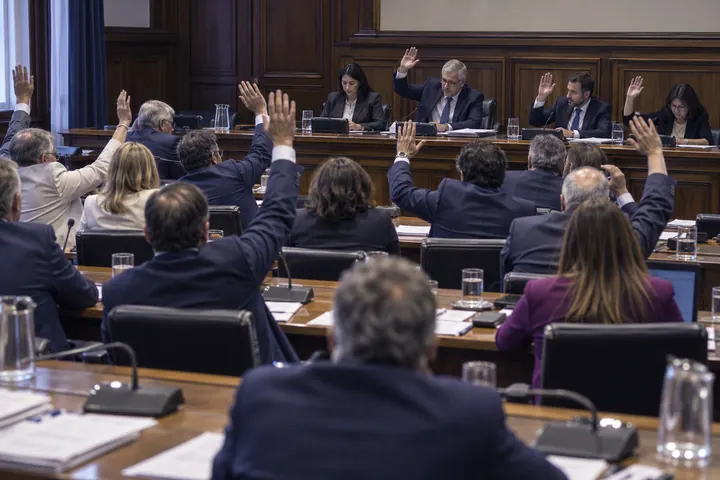 Legisladores levantando la mano para votar en una comisión