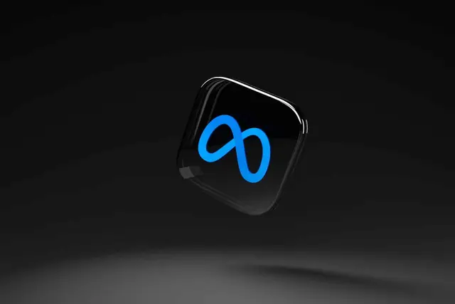 Logotipo azul de Meta, un lazo infinito luminoso, sobre un icono negro de esquinas redondeadas que flota en un fondo oscuro