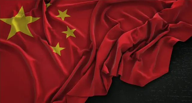 Bandera de China con una estrella amarilla grande y cuatro menores, arrugada sobre un fondo oscuro