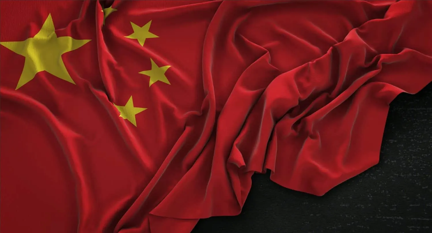 Bandera de China con una estrella amarilla grande y cuatro menores, arrugada sobre un fondo oscuro