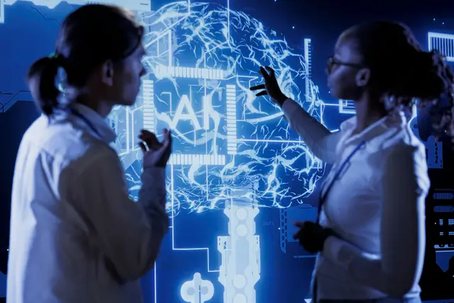 Dos personas de bata blanca frente a una gran pantalla con un cerebro luminoso y un chip con las letras AI, en un ambiente azul.