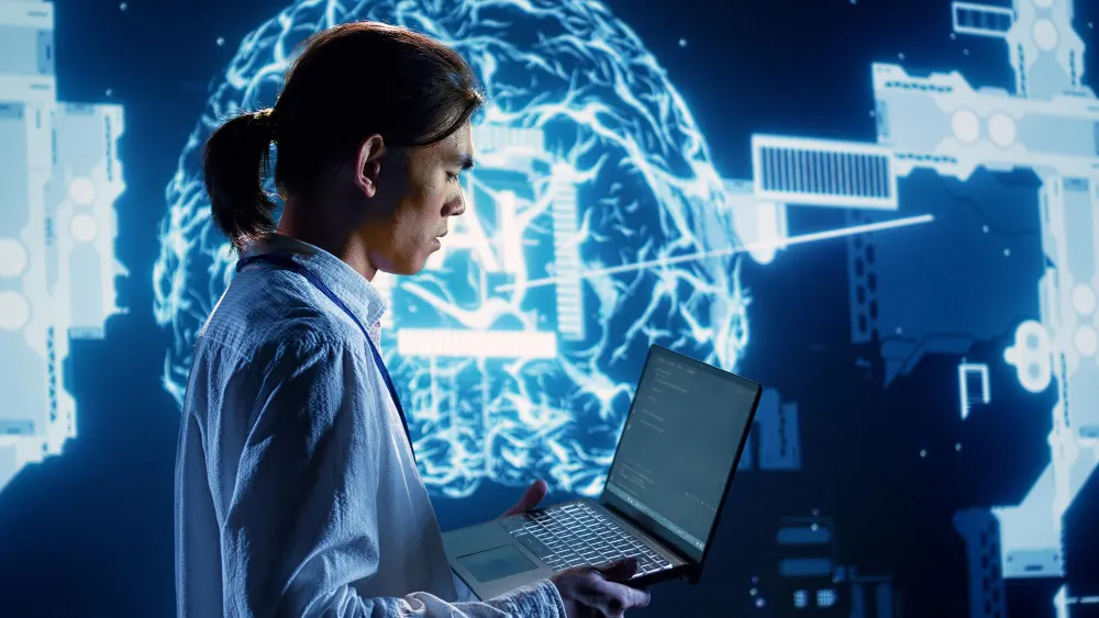 Mujer de perfil con una laptop en las manos frente a un cerebro luminoso con las letras AI y elementos de circuitos a los lados.