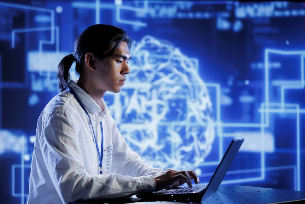 Joven de perfil que escribe en una laptop frente a un gran cerebro luminoso formado por líneas azules sobre un fondo tecnológico.