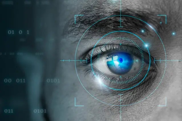 Primer plano de un ojo con una mira digital superpuesta y cifras binarias al fondo, en tonos azul y gris.