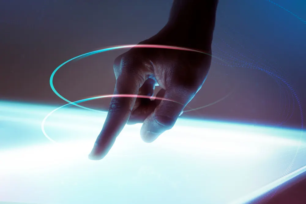 Una mano con el dedo extendido toca una superficie luminosa, rodeada por dos anillos de luz rosa y turquesa.
