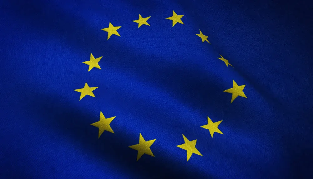 Bandera de la Unión Europea ondeando, con doce estrellas amarillas en círculo sobre fondo azul.