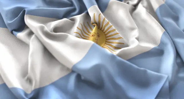 Primer plano de la bandera argentina arrugada, con franjas celestes y blancas y el Sol de Mayo en el centro.